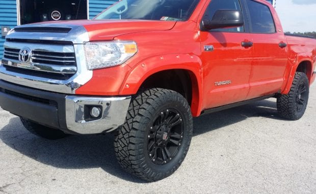 Orange tundra with fender flares XD wheels and Nitto Tires front driver side grille view