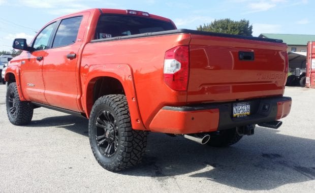 Orange tundra with fender flares XD wheels and Nitto Tires rear driver side tailgate view