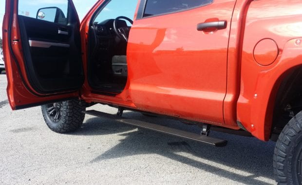 orange tundra with driver side door open AMP side steps extended