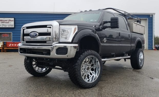 Lifted F250 work truck on chrome wheels front driver side grille view