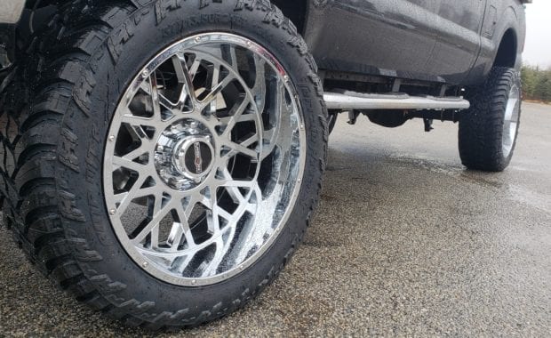 Lifted F250 work truck on chrome wheels close up on wheel