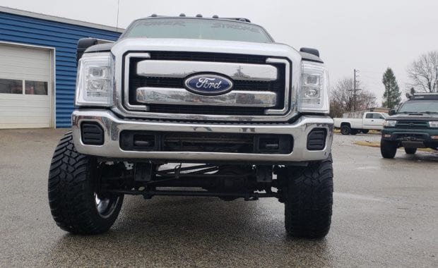 Lifted F250 work truck on chrome wheels front grille view