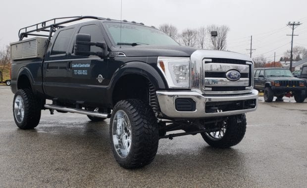 Lifted F250 work truck on chrome wheels front passenger side grille view