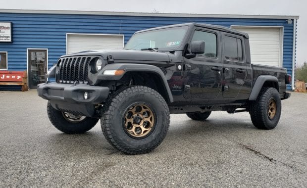 Lifted Black Jeep Gladiator on bronze wheel and tires front driver side grille view