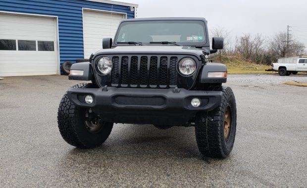 Lifted Black Jeep Gladiator on bronze wheel and tires front grille view