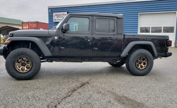 Lifted Black Jeep Gladiator on bronze wheel and tires driver side view