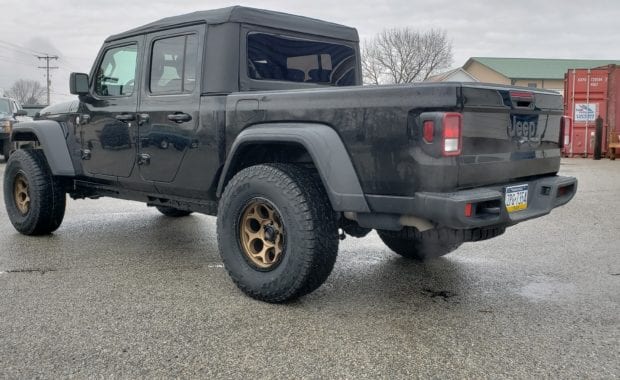 Lifted Black Jeep Gladiator on bronze wheel and tires rear driver side tailgate view