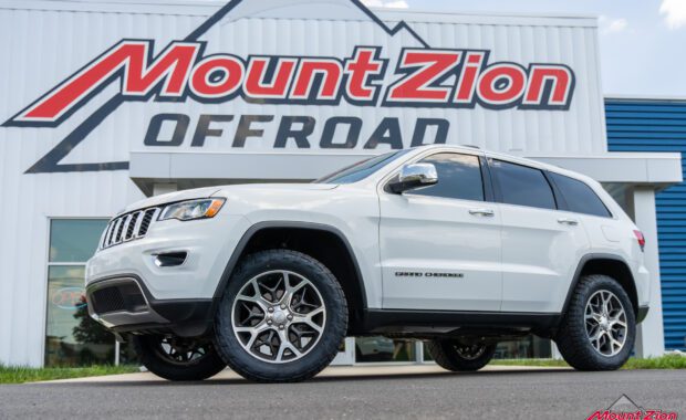 white Jeep grand cherokee with Nitto Recon grappler A/T front driver side view with mount zion offroad sign