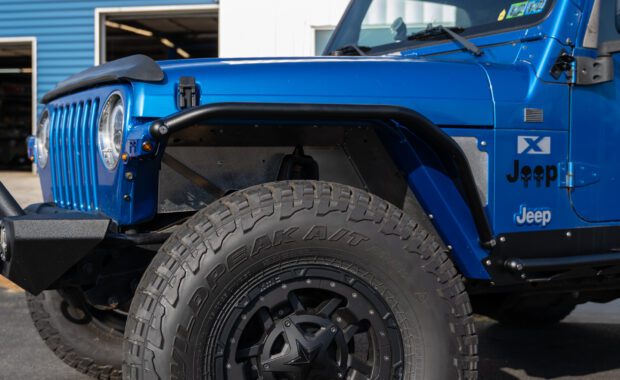 intense blue two door 2003 jeep wrangler with metal cloak step and fender on falken wildpeak tires driver side view at mount zion offroad