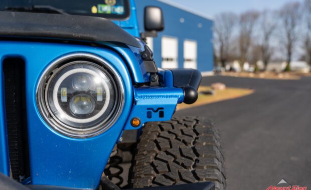 intense blue two door 2003 jeep wrangler with metal cloak step and fender on falken wildpeak tires driver side front headlight view at mount zion offroad