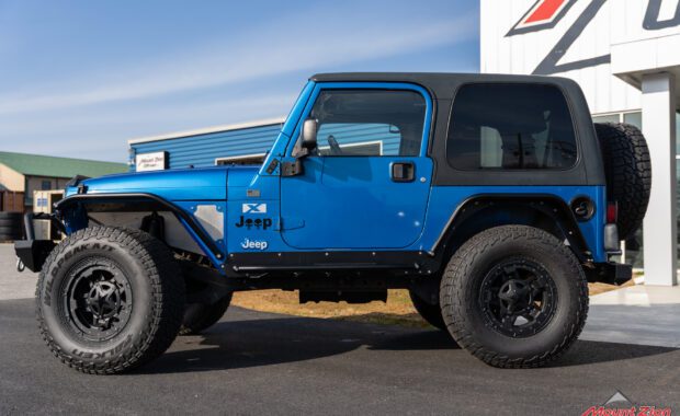 intense blue two door 2003 jeep wrangler with metal cloak step and fender on falken wildpeak tires close driver side view at mount zion offroad