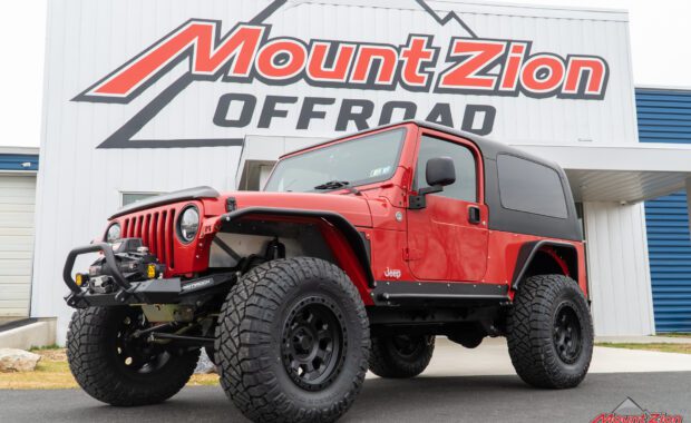 2005 two door jeep wrangler unlimited rubicon with Nitto tires and american racing wheels warn winch and metal cloak fender flares and side steps front driver side view at mount zion offroad
