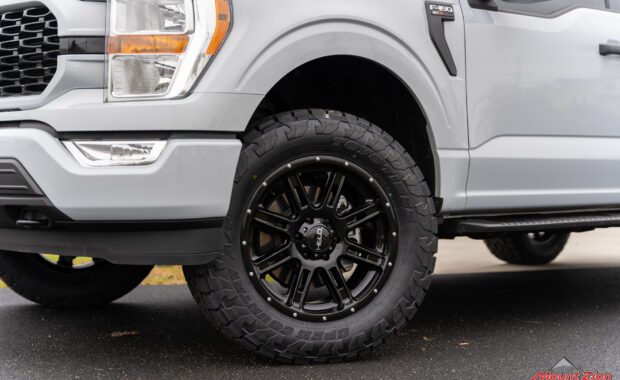 white ford f150 front driver side wheel and headlight with toyo tires open country A/T and Helo wheel