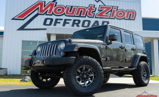 Grey 4 door jeep wrangler Sahara with Rough country suspension, Nitto Tires and Moto Metal wheels driver side front wheel and body at mount zion offroad