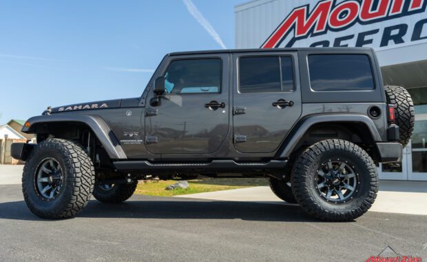 Grey 4 door jeep wrangler Sahara with Rough country suspension, Nitto Tires and Moto Metal wheels driver side view at mount zion offroad