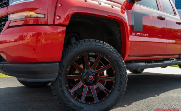Rough Country lifted Red 2017 Chevy Silverado with red fender flares and black body stripe on Black and Red Fuel wheels with falken tires