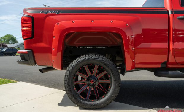 Rough Country lifted Red 2017 Chevy Silverado with red fender flares and black body stripe on Black and Red Fuel wheels rear passenger side