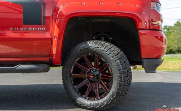 Rough Country lifted Red 2017 Chevy Silverado with red fender flares and black body stripe on Black and Red Fuel wheels and falken tires front passenger wheel well