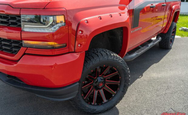 Black and Red Fuel wheels on Red 2017 Chevy Silverado with red fender flares and black body stripe front driver side view