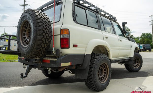 1994 toyota land cruiser lifted with black rhino wheels and toyo tires, front bumper, snorkel, roof rack, rock rails, and rear bumper rear passenger side view