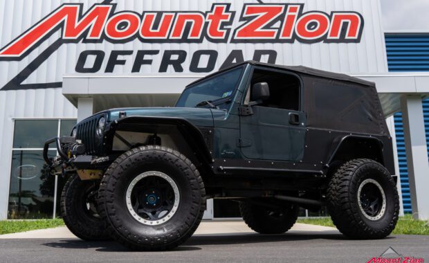 drivers side view of 2006 jeep wrangler with bumper, winch, offroad lights, lift kits and offroad tires
