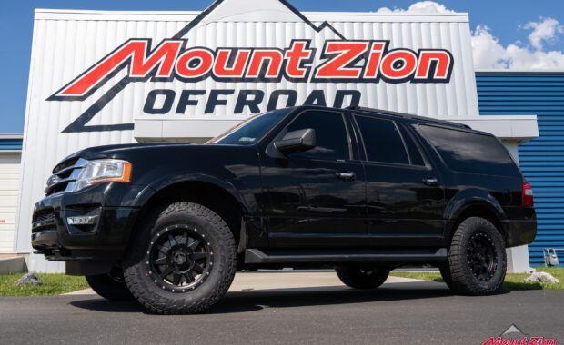 Black 2017 Ford Expedition with Bilstein suspension with method wheels and falken wildpeak tires driver side view with mount zion offroad sign