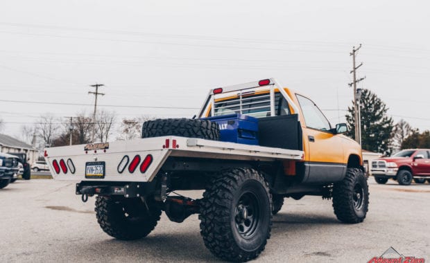 Offroad design yellow cab and flatbed truck with black wheels with blue kobalt tool box rear passenger side tailgate view
