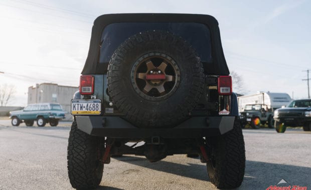 Black 4 dour soft top jeep with offroad style front bumper rotiform wheels and Nitto tires with 5th wheel tire carrier real tailgate view
