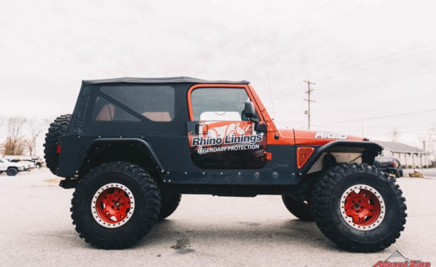 Rino linings branded two door jeep with red wheels and warn winch passenger side view