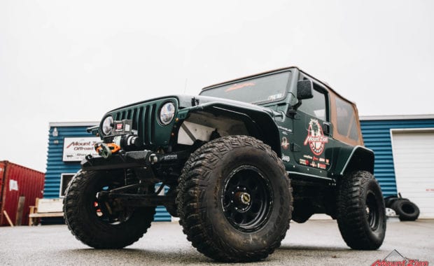 Green two door soft top jeep with Mount Zion offroad branding and winch low front driver side grille view