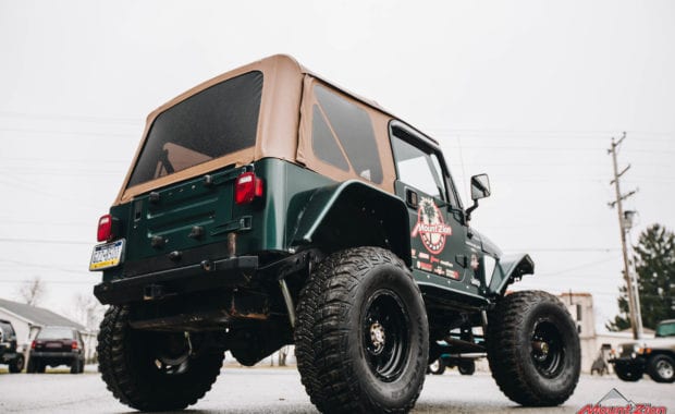 Green two door soft top jeep with Mount Zion offroad branding and winch low passenger side tailgate view