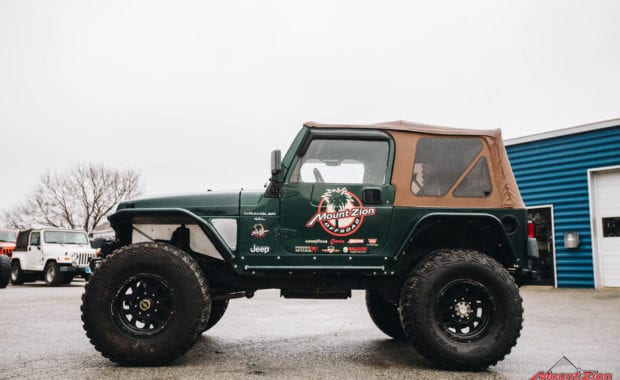 Green two door soft top jeep with Mount Zion offroad branding and winch driver side view