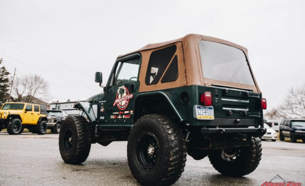 Green two door soft top jeep with Mount Zion offroad branding and winch rear driver side tailgate view