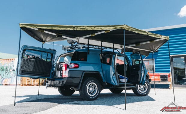 Blue FJ cruiser with roof rack and awning doors open passenger side view