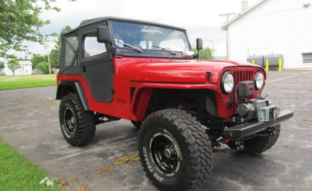 Red soft top jeep with winch on front bumper and upgraded wheels