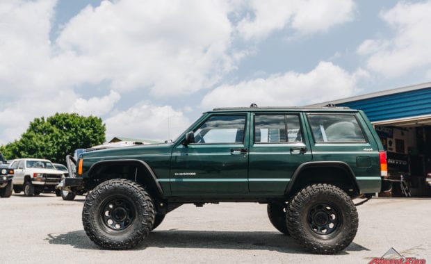 Green Jeep Grand Cherokee lifted with black offroad wheels driver side view