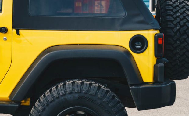 Two door yellow jeep wranlger soft top with bilstein AEV suspension and fuel wheels rear driver side