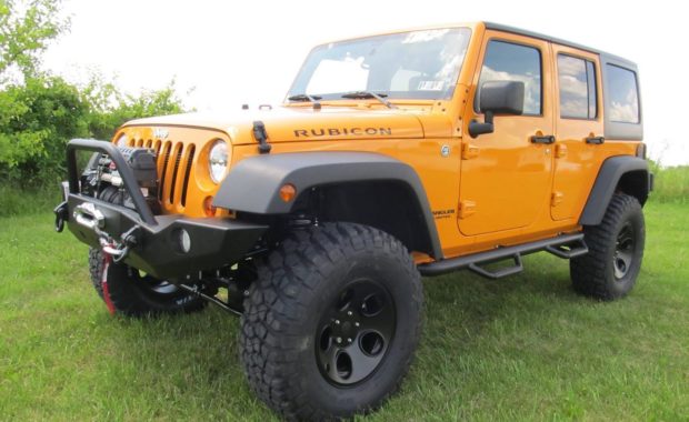 Orange Jeep wrangler rubicon with warn winch in grass