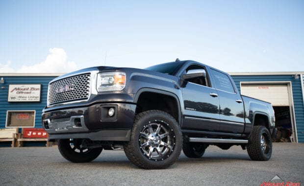 14 grey sierra denali with Rough country lift and chrome wheels front driver side grille view