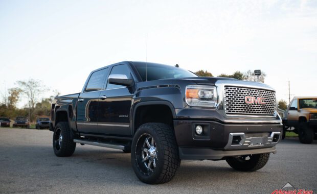 14 grey sierra denali with Rough country lift and chrome wheels front passenger side grille view