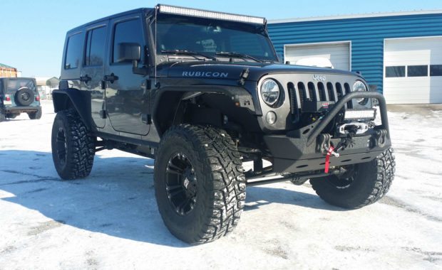 Black Jeep Rubicon with XD wheels, offroad lighting, and warn winch in snow
