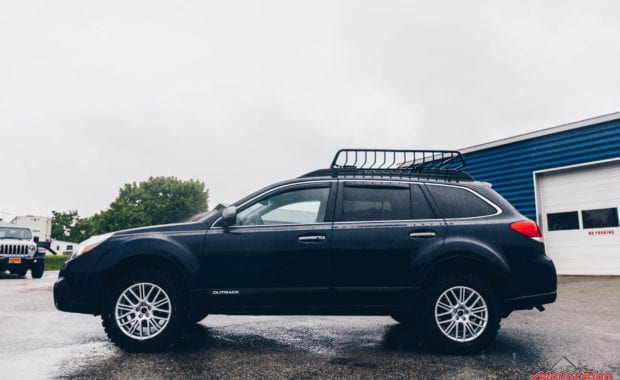 14 Subaru Outback adventure lift kit on 225/65R17 Yokohama Geolander M/T Tires with roof rack driver side view