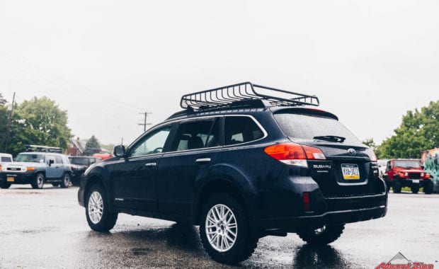 14 Subaru Outback adventure lift kit on 225/65R17 Yokohama Geolander M/T Tires with roof rack rear driver side tailgate view