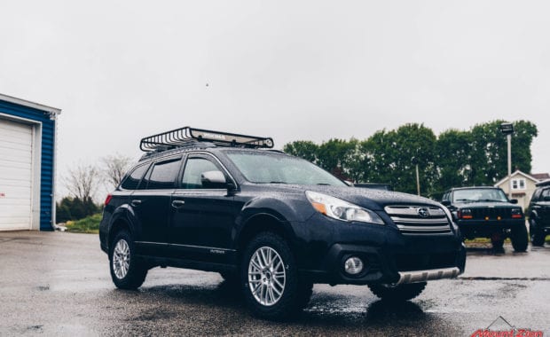 14 Subaru Outback adventure lift kit on 225/65R17 Yokohama Geolander M/T Tires with roof rack front driver side grille view