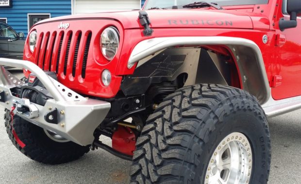 Close up of red jeep rubicon, warn winch in front bumper open country tires