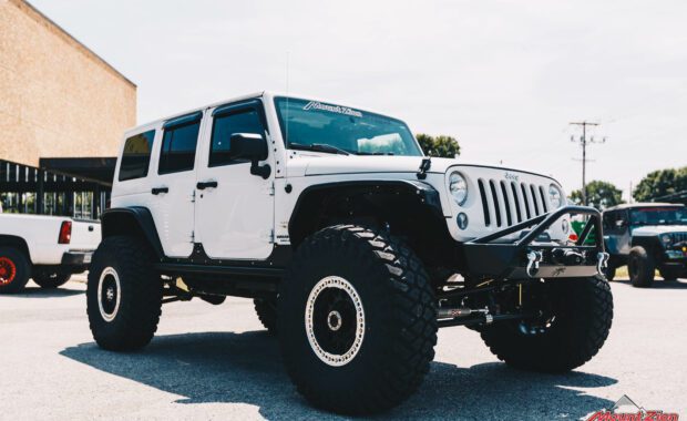 lifted white 2015 Jeep wrangler with offroad bumper with winch front passenger side grille view