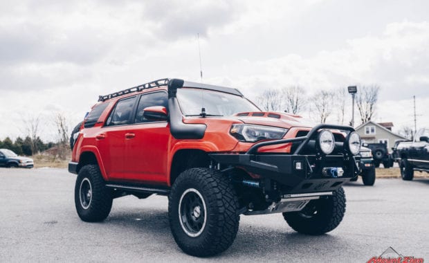 Orange 15 Toyota 4Runner with 5th wheel tire carrier and maxx traxx and snorkel front passenger side grille view