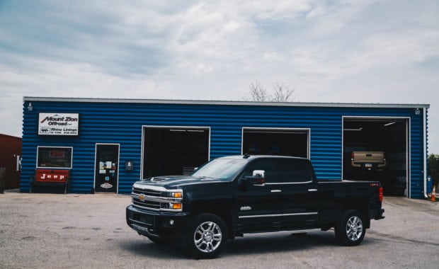 2018 Chevy silverado 2500 with chrome wheels in front of blue garage
