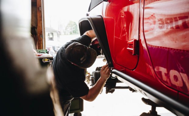 Mechanic installing rear fender flares on red jeep rubicon
