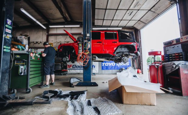 Red Jeep on lift with aftermarket protection being unboxed